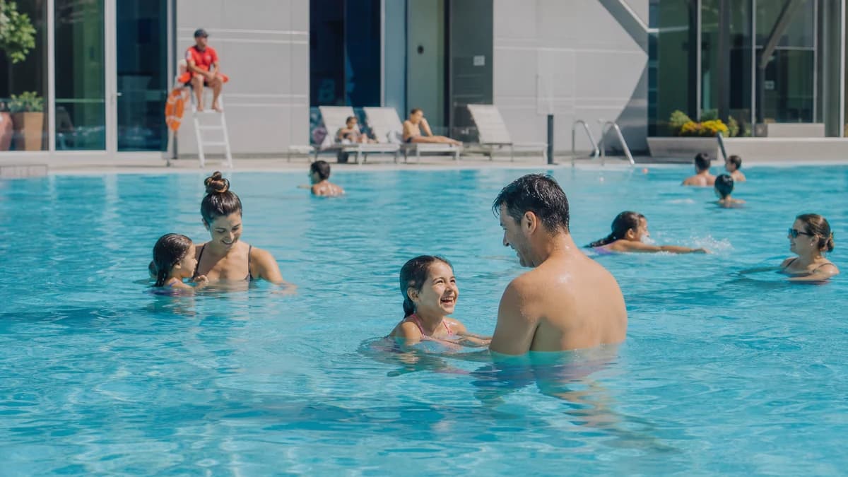 Families swimming in clear water at a well-maintained public pool